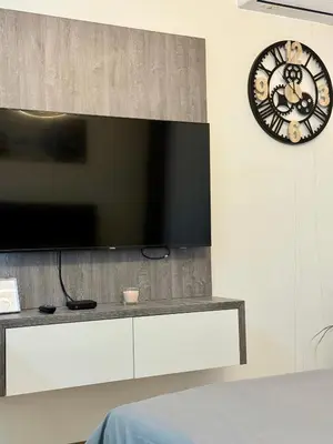 a flat screen tv on a wall with a clock at Royal Apartmani 2 in Paraćin