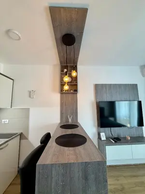 a kitchen with a wooden table and a tv at Royal Apartmani 2 in Paraćin