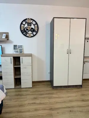 a room with a white cabinet and a clock on the wall at Royal Apartmani 1 in Paraćin