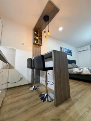 a kitchen with a bar stool in a room with a bed at Royal Apartmani 1 in Paraćin