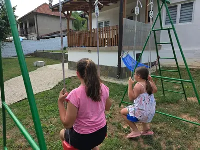 two girls playing on a swing set in a yard at Seosko domaćinstvo Trajković