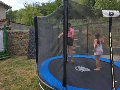 two girls are playing on a trampoline at Seosko domaćinstvo Trajković