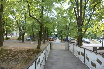a wooden walkway in a park with trees and cars at Cvetni konaci-Lenka in Vrnjačka Banja