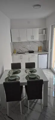 a kitchen with a table and chairs and a kitchen with white cabinets at Studio IV in Soko Banja
