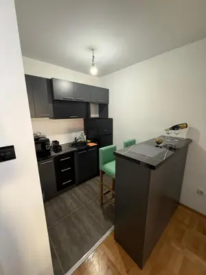 a kitchen with black cabinets and a green chair at Stan na dan Despotovac in Despotovac