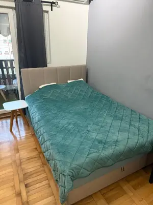 a bed in a room with a green comforter at Stan na dan Despotovac in Despotovac
