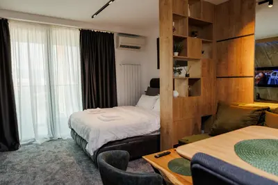 a hotel room with two beds and a table and chairs at Grey Nest - Luxury Studio Apartment in Planet Residence, Niš in Niš