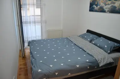 a bedroom with a bed with blue comforter and pillows at Star Apartman in Vranje