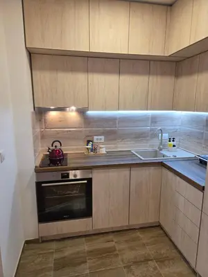a kitchen with wooden cabinets and a stove and a sink at Star Apartman in Vranje