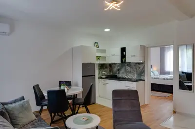 a kitchen and living room with a table and chairs at Lemona Apartmani Vrnjačka Banja in Vrnjci