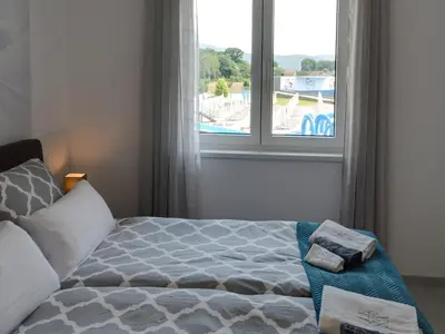 a bedroom with a bed and a large window at Lemona Apartmani Vrnjačka Banja in Vrnjci