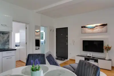 a living room with a table and chairs and a television at Lemona Apartmani Vrnjačka Banja in Vrnjci