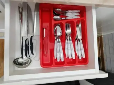 a red tray with silver utensils in a cabinet at Studio-apartman DM lux in Vrnjačka Banja