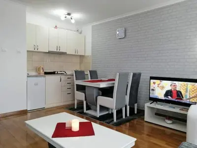 a kitchen and dining room with a table and a television at Studio-apartman DM lux in Vrnjačka Banja