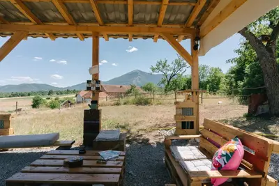 a wooden bench under a pavilion with mountains in the background at Sve Mir in Boljevac