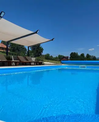 a large blue swimming pool with chairs and an umbrella at LaLuna Houses in Lipova