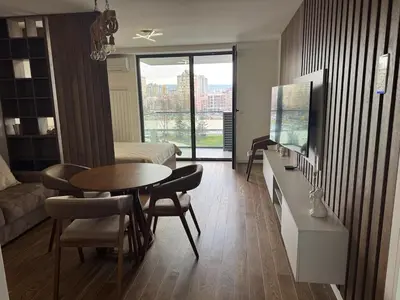 a living room with a table and a room with a bed at Palas Central Delux & SPA in Niš