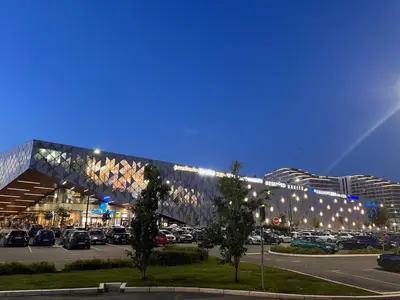 a parking lot with a large building with cars parked at Palas Central Delux & SPA in Niš