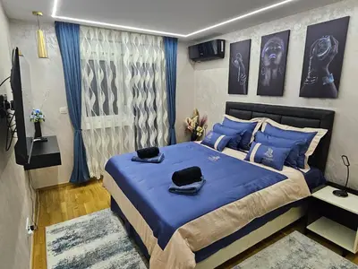 a bedroom with a blue bed with blue pillows at POSEJDON DELUXe 3 in Vrnjačka Banja
