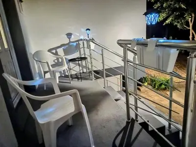 a balcony with white chairs and a table and railing at Home Well Apartman Vranje in Vranje
