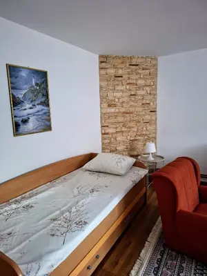a bedroom with a bed and a chair at Home Well Apartman Vranje in Vranje