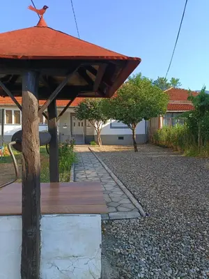 a wooden bench with a roof on a gravel road at Home Well Apartman Vranje in Vranje