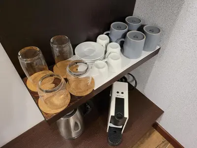 a shelf with cups and glasses and a remote control at Zoi i Nika Kopaonik in Kopaonik