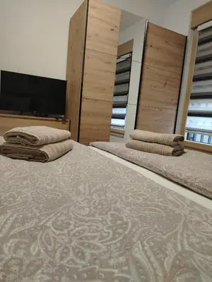 a bedroom with two beds and a flat screen tv at Apartman Amber Vrnjačka Banja in Vrnjci