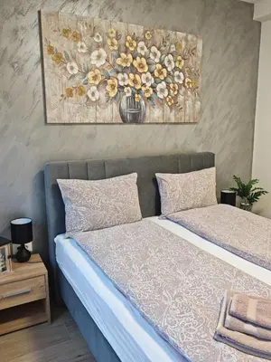 a bedroom with a bed with a painting on the wall at Apartman Amber Vrnjačka Banja in Vrnjci