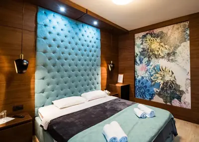 a bedroom with a large bed with a blue headboard at Hotel Zeleni Vir in Niš