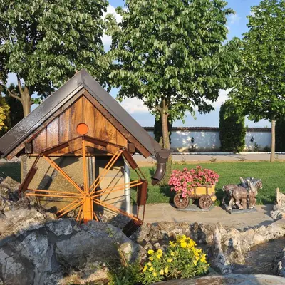 a model of a wooden barn with two horses and flowers at Hotel Zeleni Vir in Niš