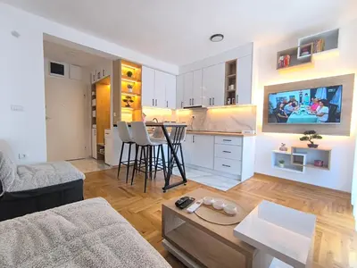 a living room with a couch and a kitchen with a table at Apartman Vujanac in Vrnjačka Banja