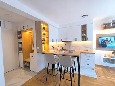 a kitchen with white cabinets and bar stools at Apartman Vujanac in Vrnjačka Banja