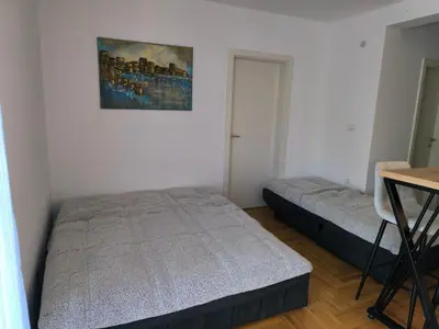 a bedroom with two beds and a table in it at Apartman Vujanac in Vrnjačka Banja