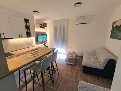 a kitchen and living room with a table and a couch at Apartman Vujanac in Vrnjačka Banja