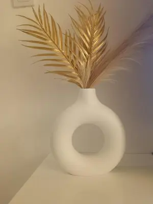 a white vase with feathers in it on a table at Udoban kutak 2 in Niš