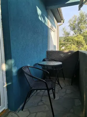 two chairs and tables on a balcony with a blue wall at Apartman Pače in Raška