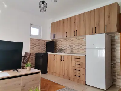 a kitchen with wooden cabinets and a white refrigerator at Apartman Pače in Raška
