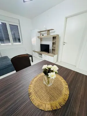 a room with a table with a vase of flowers on it at Aqua Apartments 3 in Jagodina