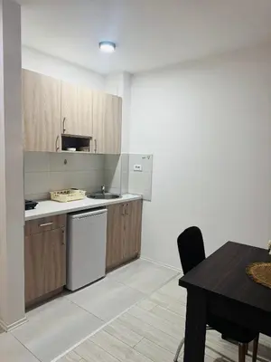 a kitchen with wooden cabinets and a table with a chair at Aqua Apartments 3 in Jagodina