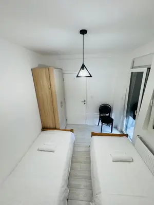 a small room with two beds and a chair at Aqua Apartments 3 in Jagodina