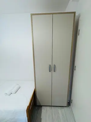 a bedroom with a white cabinet next to a bed at Aqua Apartments 3 in Jagodina