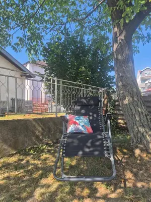 a black chair sitting next to a tree at Toplica in Vrnjačka Banja
