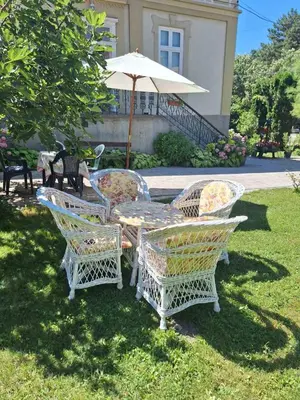 a table and chairs with an umbrella in the grass at Kuća Petrovića in Aleksandrovac