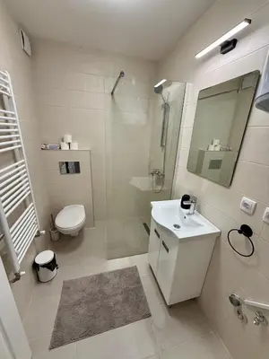 a white bathroom with a toilet and a sink at Royal Apartmani 3 in Paraćin