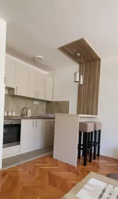a kitchen with white cabinets and a wooden floor at Studio Inn 