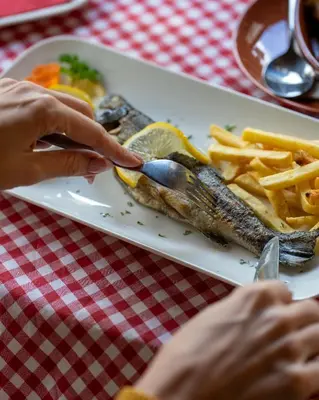 a plate of food with a fish and french fries at Lisine Lepo Mesto Guesthouse & Spa in Strmosten