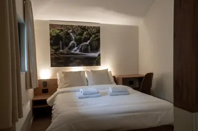 a bedroom with a white bed with a painting on the wall at Lisine Lepo Mesto Guesthouse & Spa in Strmosten
