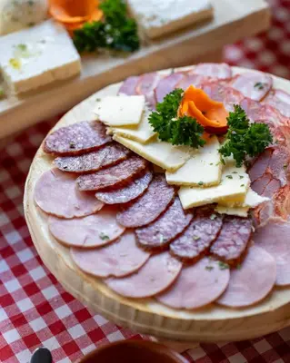 a plate of meats and cheese on a table at Lisine Lepo Mesto Guesthouse & Spa in Strmosten