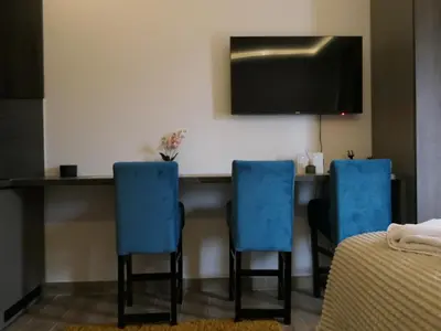 a room with a table with blue chairs and a television at Andromeda Apartment Residence Hill Kopaonik in Kopaonik